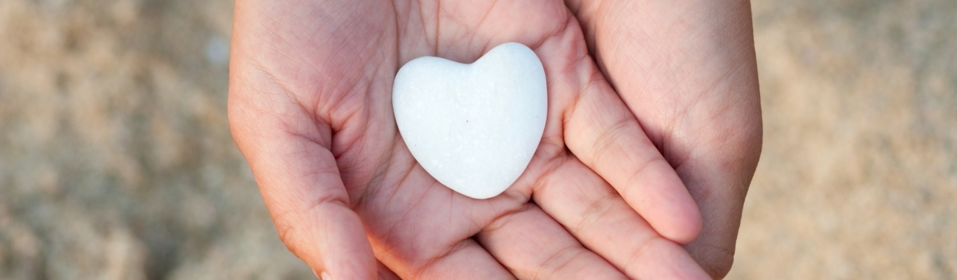 Hands holding stone that is shaped like a heart